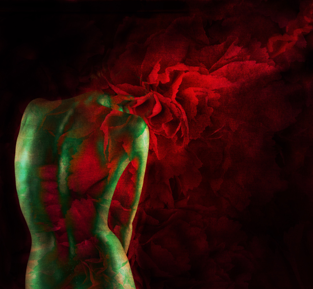 A woman displays a vibrant arrangement of red and green flowers on her back, showcasing a striking floral design.